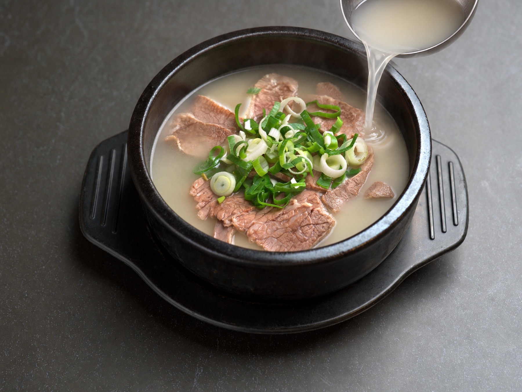 Broth being poured into a seolleongtang bowl to order